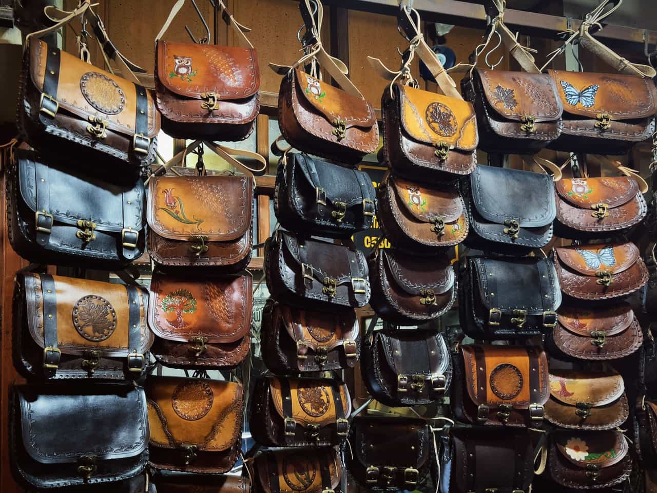 A brown leather crossbody bag resting on a neutral surface